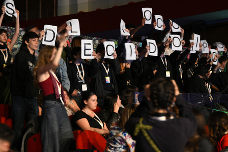 Los estudiantes exhiben carteles durante el discurso de la ministra.