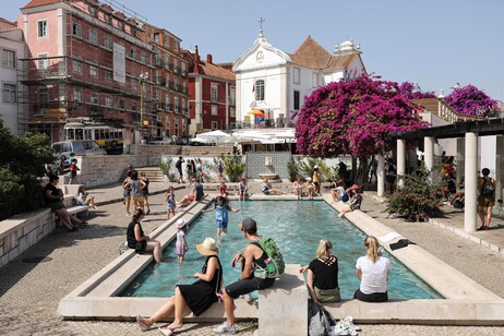 Turistas se refrescam em fonte em Lisboa, capital de Portugal