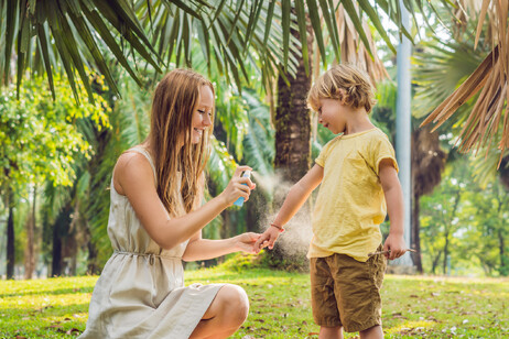 Una mamma spruzza spray anti insetti al figlio foto iStock.