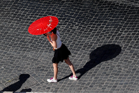 Pedestre se protege contra onda de calor em Roma, capital da Itália, em julho de 2024