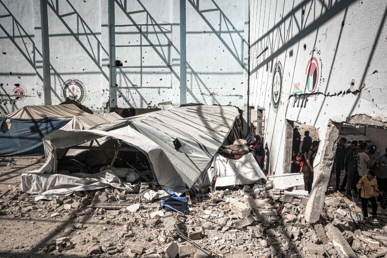 People inspect destruction next to a partially-collapsed tent shelter in the yard of the Shuhada © ANSA/AFP