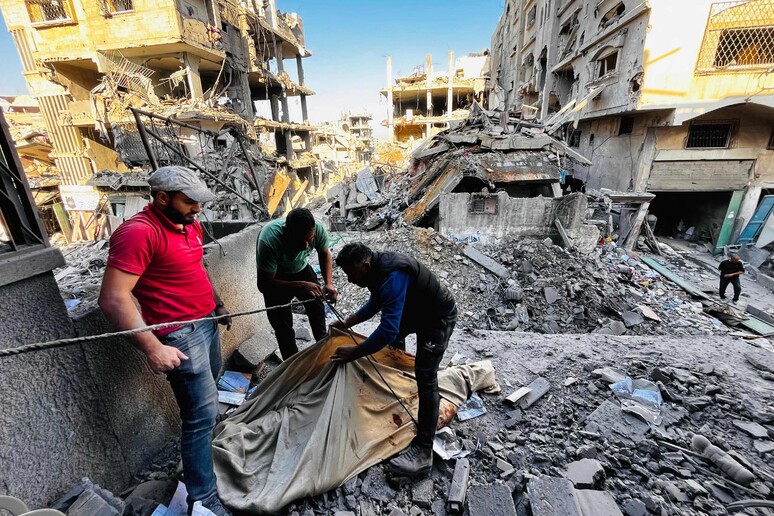 Palestinian first responders remove a body from the rubble of a building © ANSA/AFP