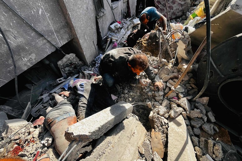 Palestinians remove bodies from the rubble of a building hit by an Israeli strike in Beit Lahia © ANSA/AFP