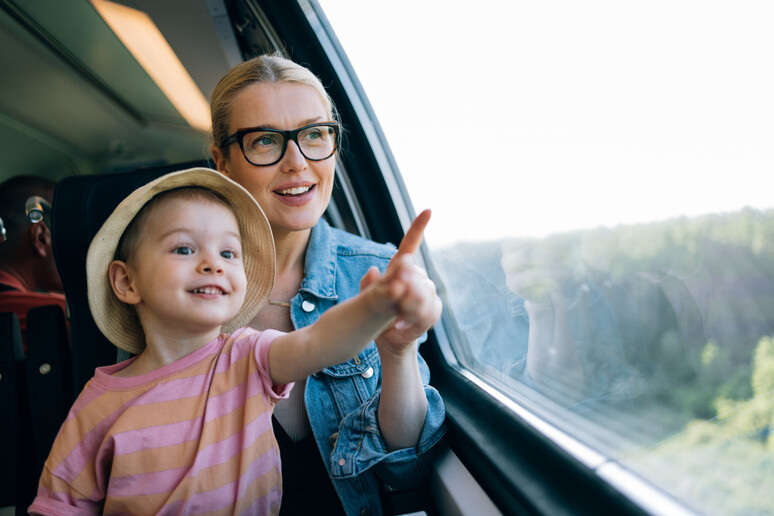 Una mamma con un bambino guardano il paesaggio in treno foto iStock. - RIPRODUZIONE RISERVATA