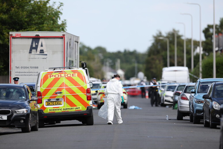 A police scenes of crime officer (SOCO) carries an evidence bag in Hart Street in Southport, Britain - RIPRODUZIONE RISERVATA